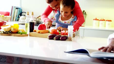 Mother-assisting-daughter-to-chop-vegetables-in-kitchen-4k