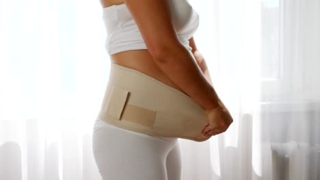 woman-wears-adjustable-support-for-prenatal-or-postpartum-comfort,-close-up-pregnant-woman-tighten-bandage