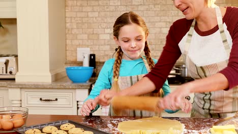 Lächelnde-Mutter-und-Tochter-trägt-Schürze-rollenden-Teig-zusammen-4-K-4k