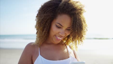 Ethnische-weiblich-mit-Smartphone-genießen-Spaß-am-Strand