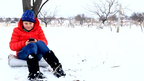 Child-using-smartphone-in-winter-park