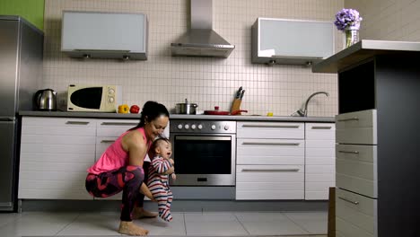 Smiling-woman-doing-lunges-with-baby-son-in-hands