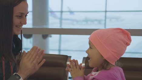 Yound-mother-and-little-cute-daughter-having-fun-at-airport-in-slow-motion.