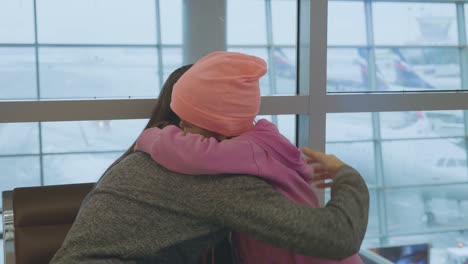 Joven-madre-e-hija-poco-Linda-abrazan-suavemente-en-el-aeropuerto-en-cámara-lenta.