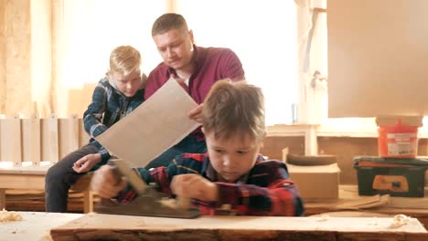 Familie,-Schreinerei,-Holzarbeiten-und-Menschen-Konzept.-Vater-lehrt-Sohn-Zimmerei.