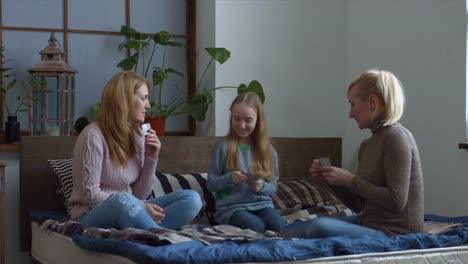 Joyful-family-with-child-playing-cards-on-the-bed