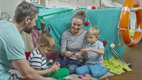 Los-felices-padres-y-dos-niños-pequeños-jugando-con-plastilina-juntos