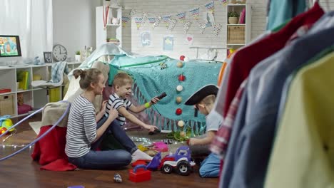 Eltern-und-zwei-kleine-Jungs-spielen-mit-Spielzeug-Schwerter