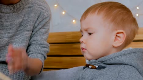 Young-mother-and-her-baby-son-reading-book-at-home