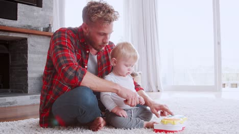 Vater-mit-kleinen-Sohn-in-ihrem-Wohnzimmer-spielen