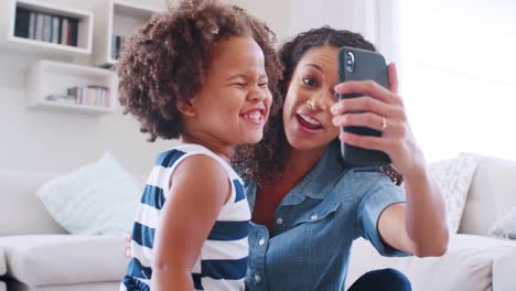 Junge-schwarze-Frau-und-Tochter-nehmen-Selfie-Grimasse