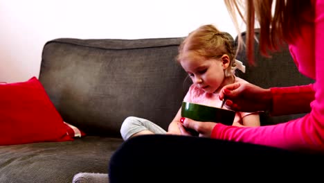 Mom-feeds-a-little-girl-who-can't-take-her-eyes-off-her-smartphone