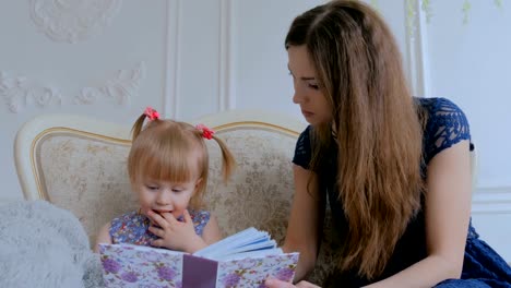 Junge-Mutter-und-ihre-kleine-Tochter-suchen-Fotobuch