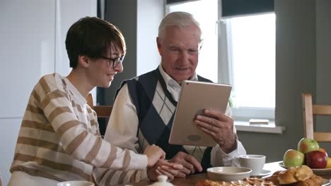 Enkelin-helfen-Großvater-mit-Tablet