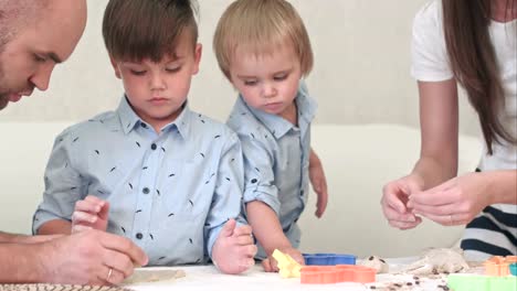 Young-happy-parents-showing-their-children-how-to-make-cookies