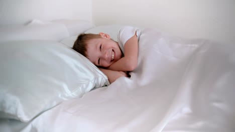 Sieben-Jahre-alten-Jungen-gerade-aufgewacht-und-lacht-beim-liegen-im-Bett.