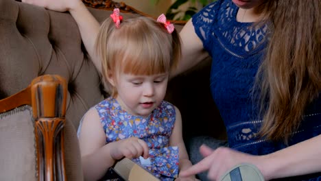 Young-mother-and-her-baby-daughter-reading-book-at-home