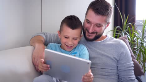 Lächelnd,-Vater-und-Sohn-mit-Tablet-sitzend-auf-sofa