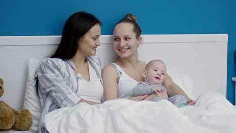 Happy-Female-Couple-in-Bed-with-Cute-Baby