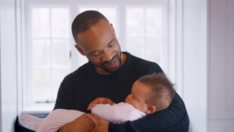 New-Father-Cuddling-Sleeping-Baby-Girl-In-Nursery-At-Home