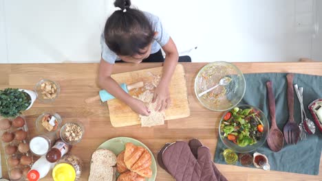 Top-view-little-girl-cooks-in-the-kitchen-at-home