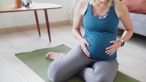 Active-fit-pregnant-woman-feeling-belly-baby-kicking-while-exercising