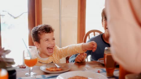 Joven-que-se-divierte-comiendo-saludable-desayuno-con-la-familia