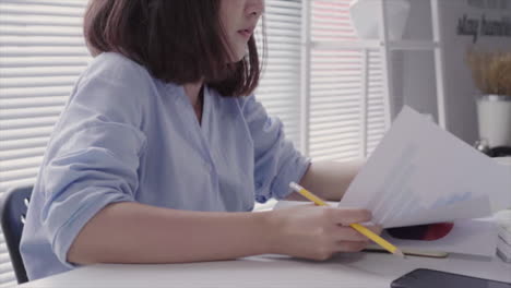 Beautiful-young-strain-asian-woman-working-on-laptop-while-sitting-in-a-living-room-at-home.-Asian-business-woman-working-in-her-home-office.