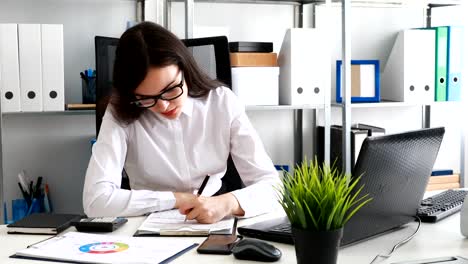 geschäftsfrau-füllen-Dokumente-und-arbeiten-am-Laptop-im-modernen-Büro