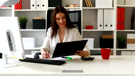 brunette-geschäftsfrau-arbeiten-mit-Dokumenten-in-hellen-Büro