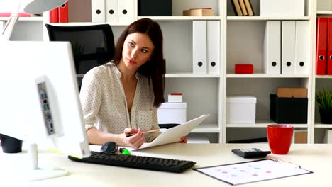 businesswoman-sitting-in-office-chair-and-looking-in-documents