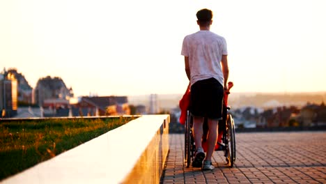 Young-Man-Rolls-Disabled-Girl-With-Red-Hair,-Tells-And-Shows-His-Hand