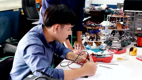 Male-engineer-training-how-to-work-with-robotics-prototype-in-workshop.-People-with-Science,-Technology,-Education-concept.