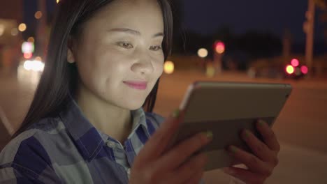 Young-Asian-woman-using-tablet-in-the-city-streets