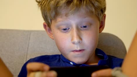 Little-boy-playing-the-online-game-using-the-mobile-smartphone-gadget-device-4K-footage