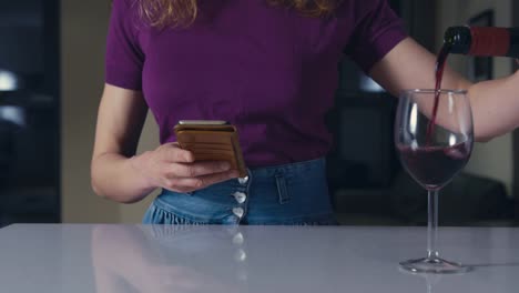 Woman-using-smartphone-pouring-wine