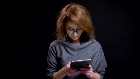 Closeup-portrait-of-middle-aged-modern-female-typing-on-the-tablet-casually-with-background-isolated-on-black