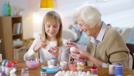 Abuela-y-nieta-pintando-huevos-y-sonriendo