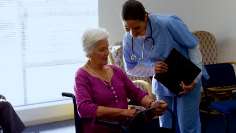 Vista-frontal-de-mujer-caucásica-médico-y-anciana-discutiendo-sobre-la-tableta-digital-en-enfermería-hom