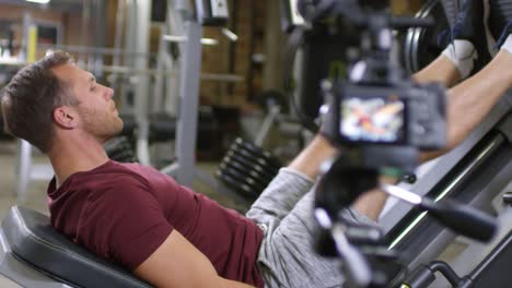 Gym-Trainer-Showing-Leg-Press-Exercise-on-Camera