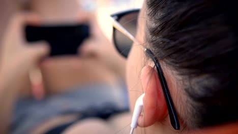 Chica-escuchando-música-en-los-auriculares-y-el-surf-en-los-mensajes-de-las-redes-sociales,-relajación-vacaciones-de-verano