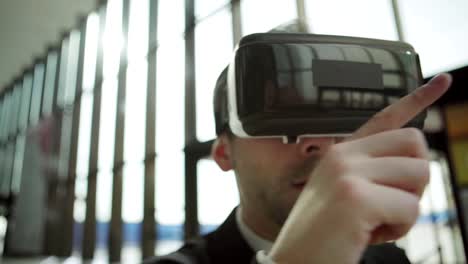 Nahaufnahme-des-Mittelaltersunternehmers-in-der-Virtual-Reality-Headset,-das-mit-visualisierten-Analysedaten-in-der-Bürohalle-arbeitet