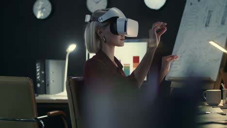 Business-woman-swiping-hands-in-interactive-space-in-night-office