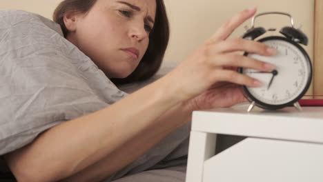 Mujer-se-despierta-del-despertador-y-revisa-su-teléfono-móvil-en-la-cama