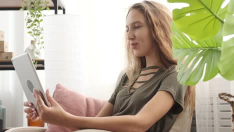 Teenage-girl-video-chatting-using-digital-tablet-on-sofa