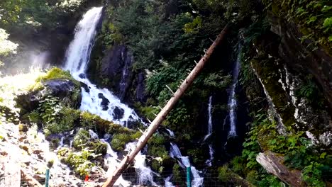 Schöne-frische-Wasserfall-unter-hohen-Felsen-witth-Grün-in-Sotschi,-Russland