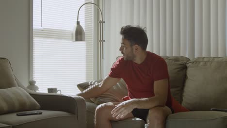 Man-throws-cellphone-in-couch,-then-picks-up-a-book-and-enjoys-it