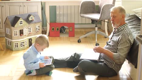 grandfather-and-grandson-spend-time-in-living-room-looking-through-the-family-album