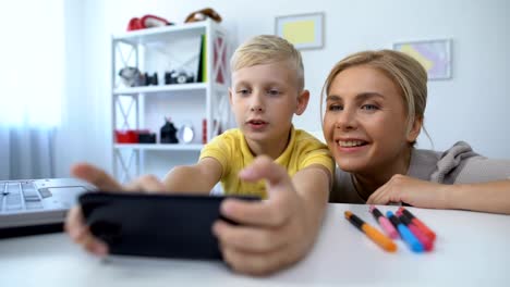 Niño-pequeño-jugando-nuevo-juego-de-teléfono-celular,-madre-dando-consejos-a-hijo,-pasatiempo