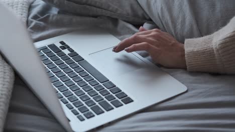 Woman-using-laptop-while-resting-in-bed